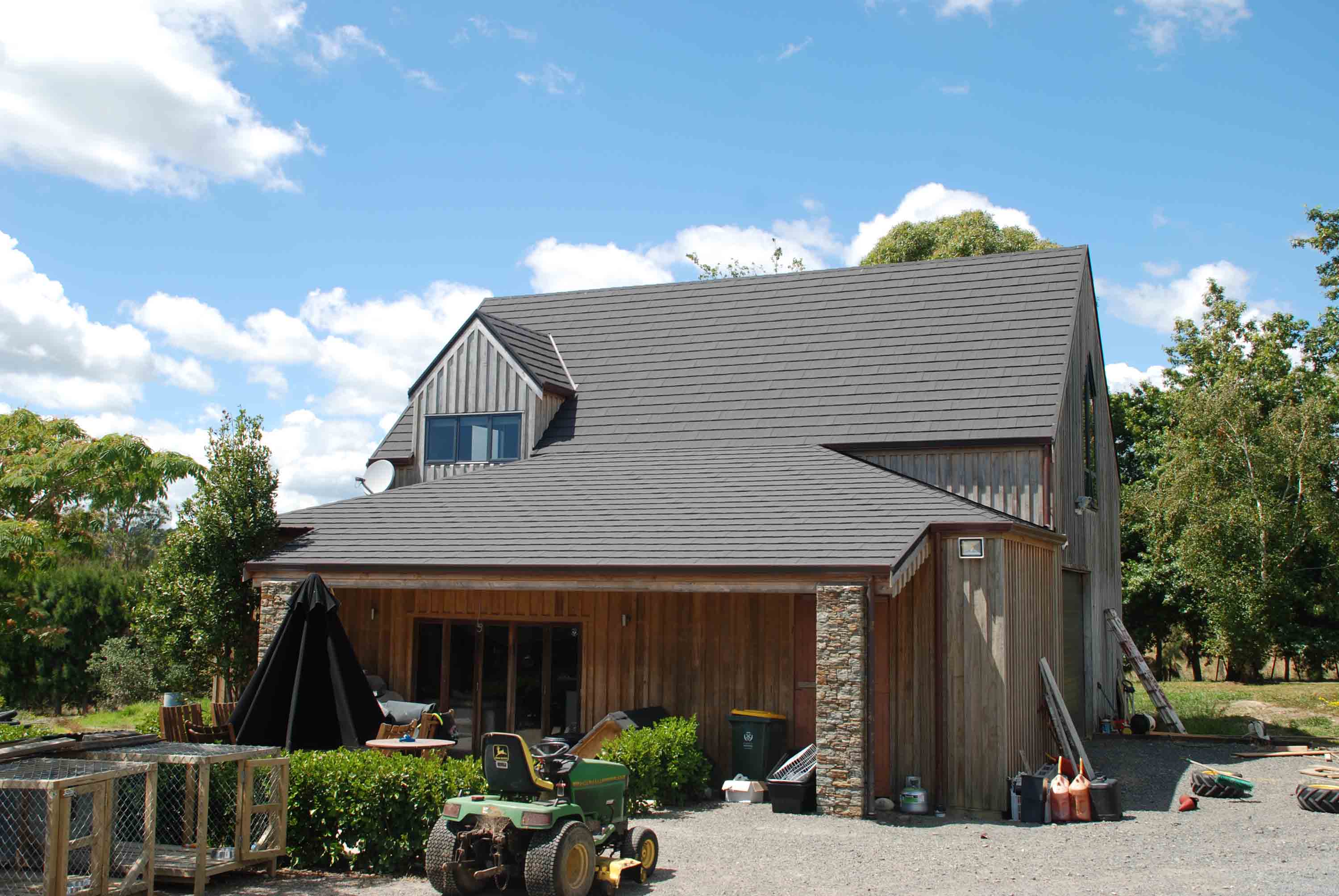 Wooden home in rural setting with vertical cladding re-roofed with CF Slate steel roofing