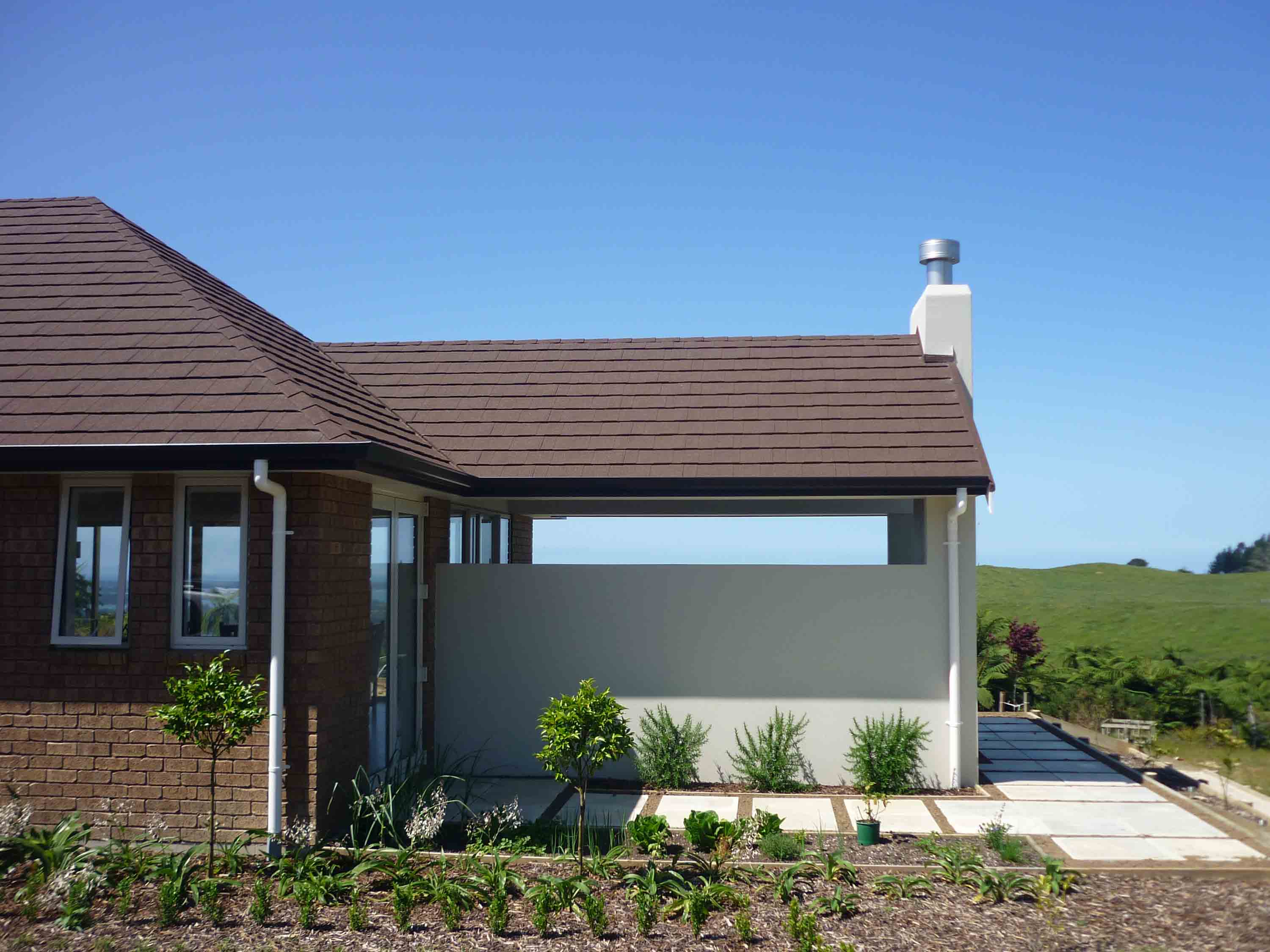 Countryside home roofed in CF Slate, Brown Bark. Green grass and blue sky.